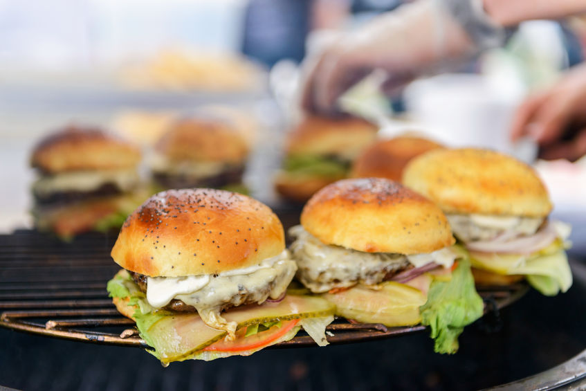 Chef making beef burgers outdoor on open kitchen international food festival event.