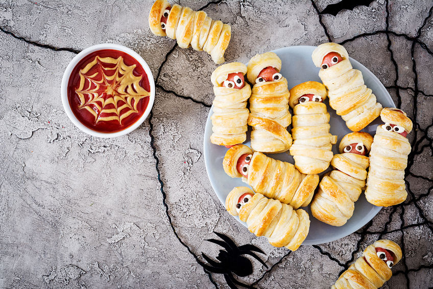 Scary sausage mummies in dough with funny eyes on table