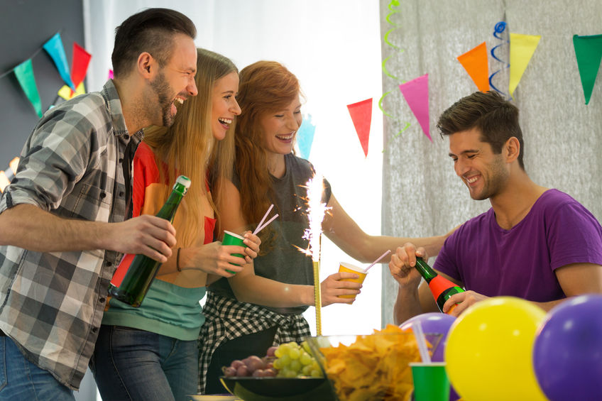 Students having home party, man holding bottle of champagne