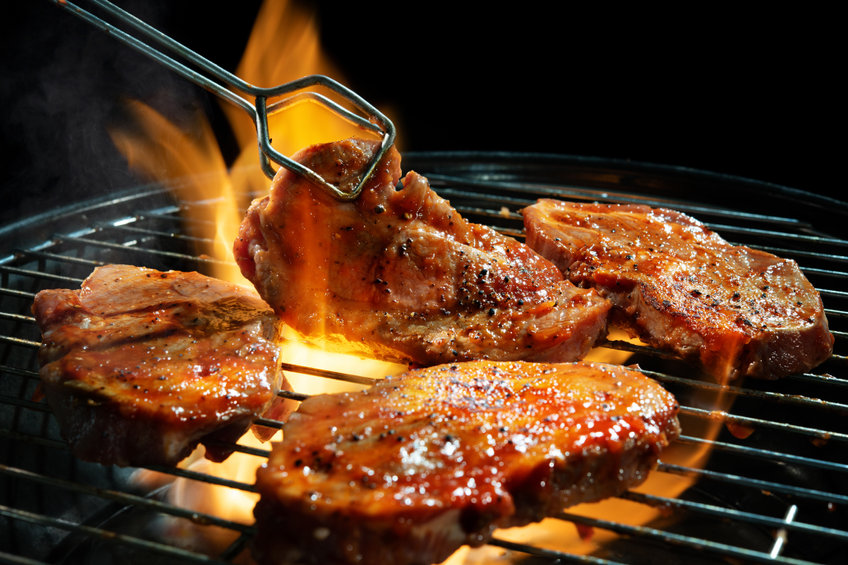 pork steaks on barbecue grill with flames