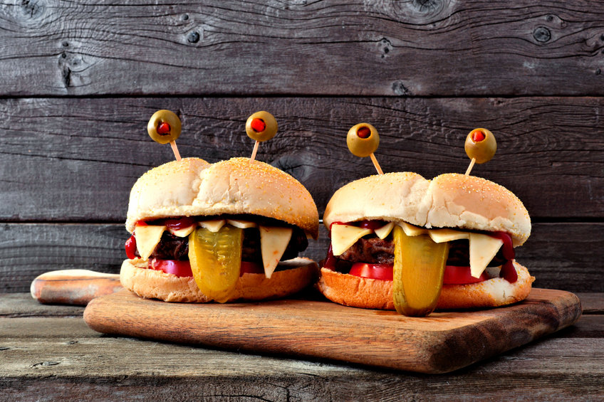 Halloween monster hamburgers on a paddle board against an old wood 