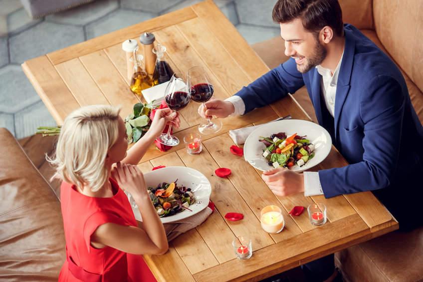Young couple on date sitting eating salad