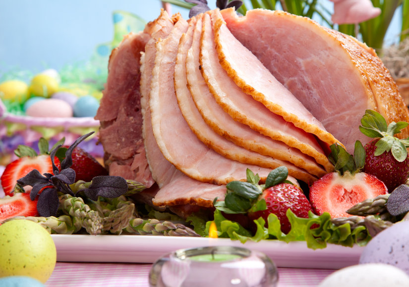 Honey ham on Easter table with eggs, flowers and decoration