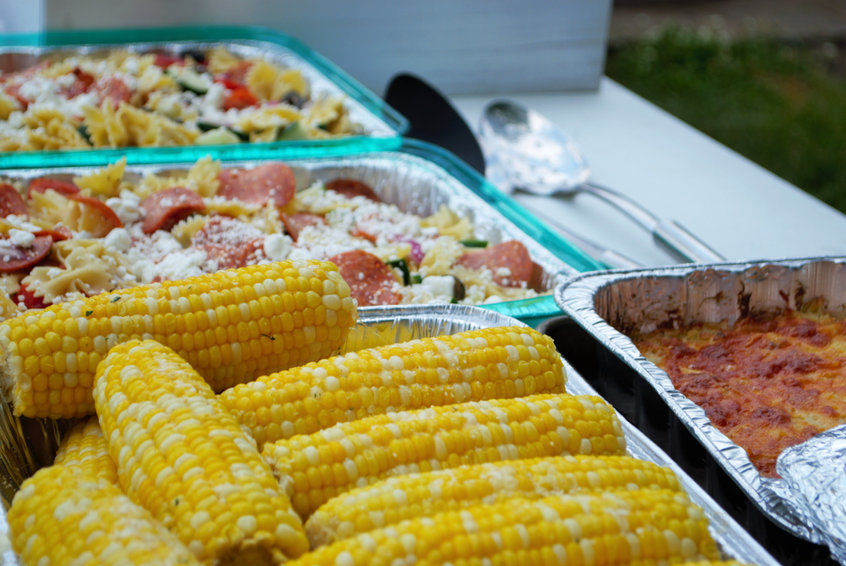 large assortment of dishes on the food table at a picnic